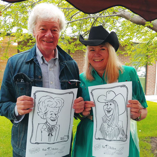 Two happy Stampede party guests with their caricatures.